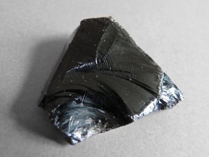 This is a small piece of raw obsidian. It resembles a piece of broken black glass.