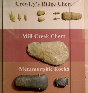 Several beige and brown chert artifacts. These include a number of arrowheads, a bladelet and scraping tool.