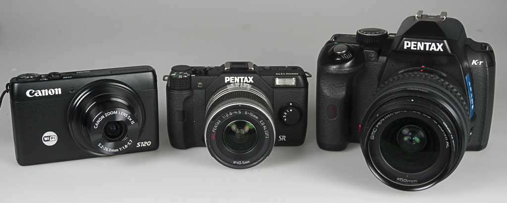 Three cameras. Left to right. Canon point-and-shoot, Penax mirrorless, and Pentax K-r DSLR.